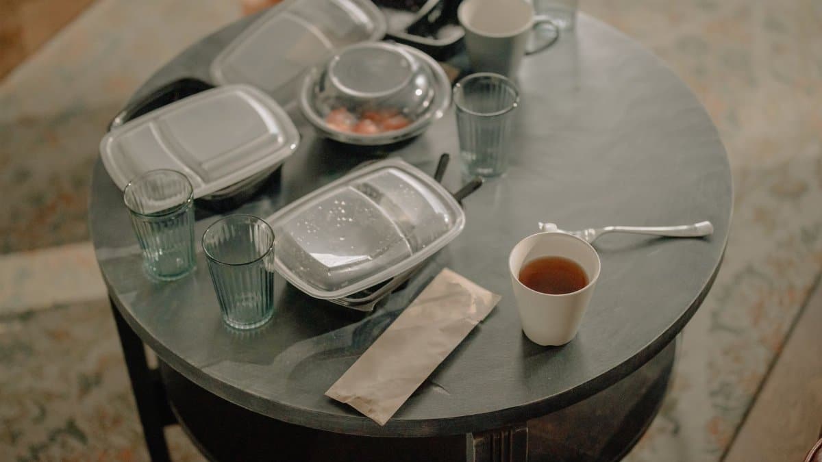A cozy home setting with a table covered in takeaway food containers and used dishes.