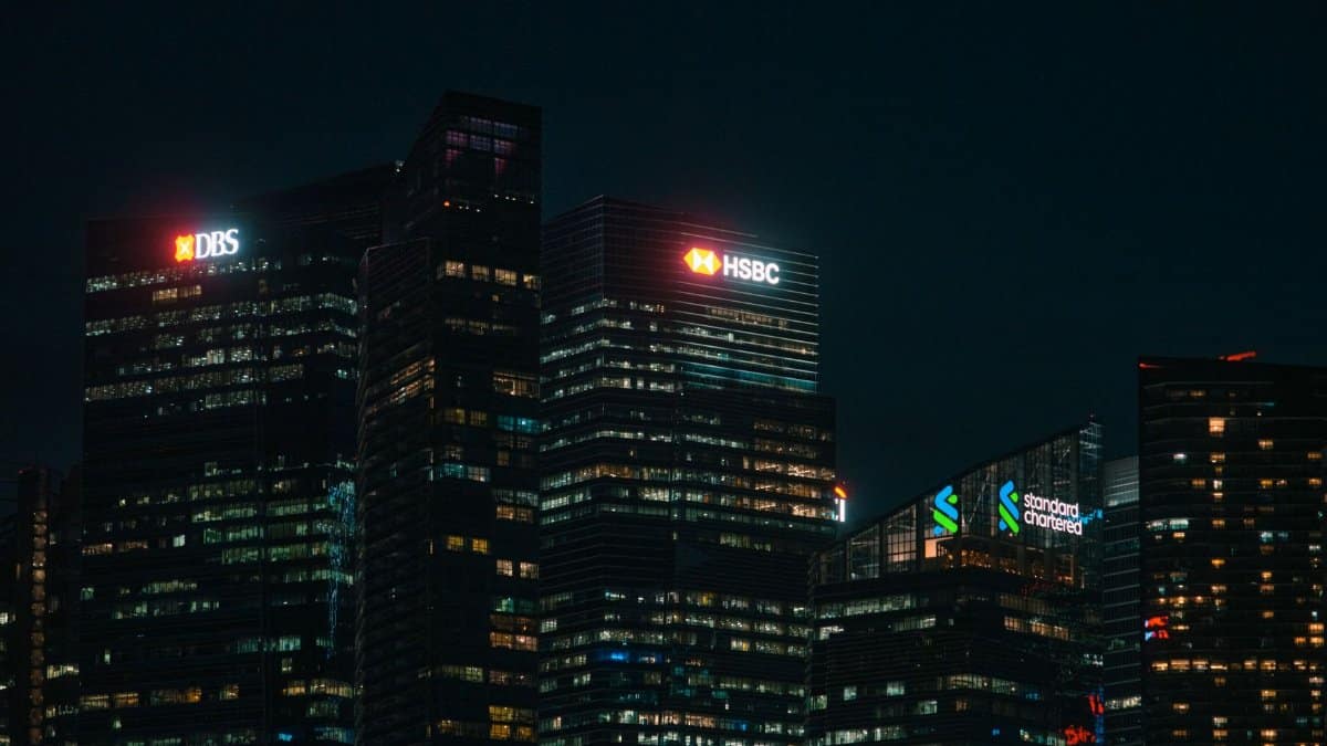 Illuminated city skyscrapers of major banks in Singapore's financial district at night.