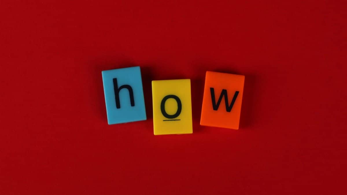 Colorful letter tiles spelling 'How' on a vibrant red background, ideal for educational content.