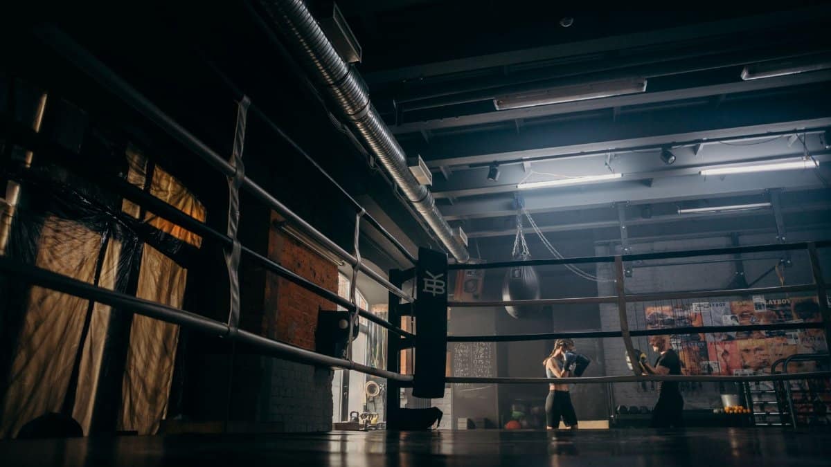Two boxers sparring in a dimly lit gym, practicing punches with dedication.