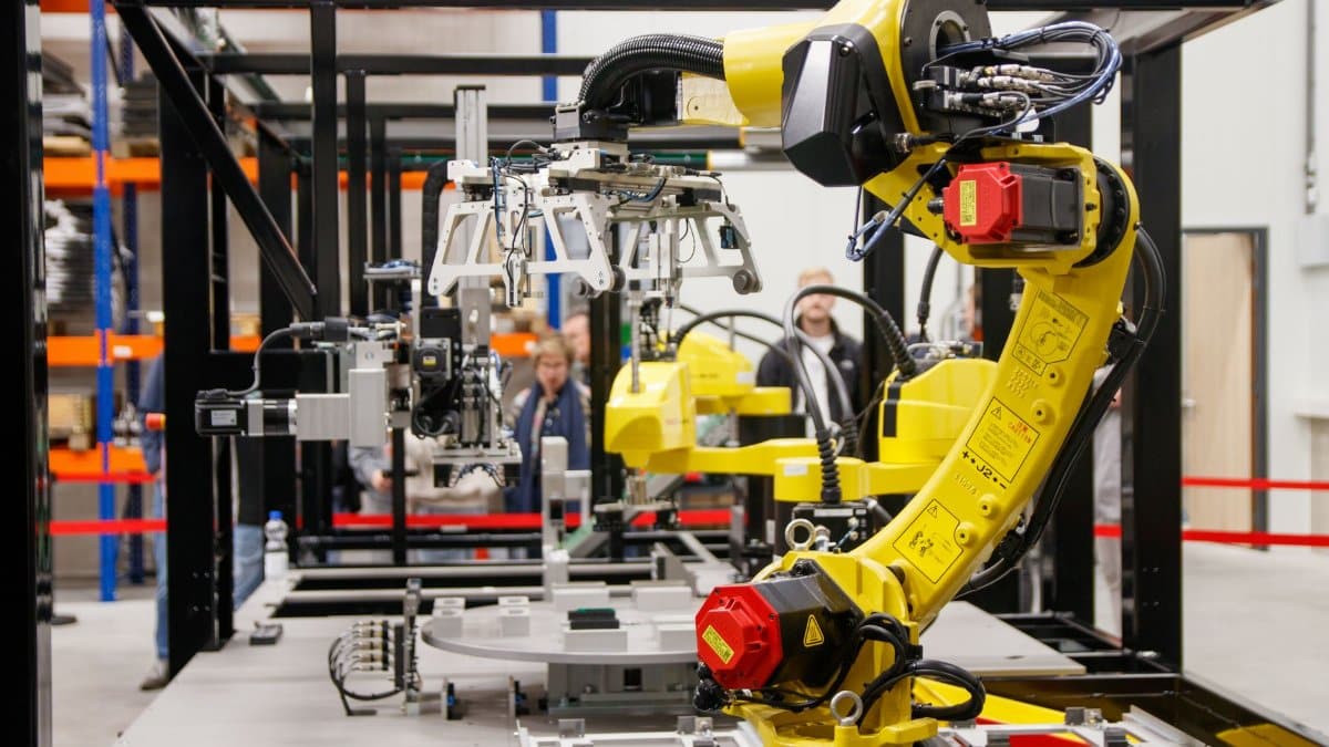 Close-up of a yellow industrial robotic arm in action at a modern manufacturing facility.