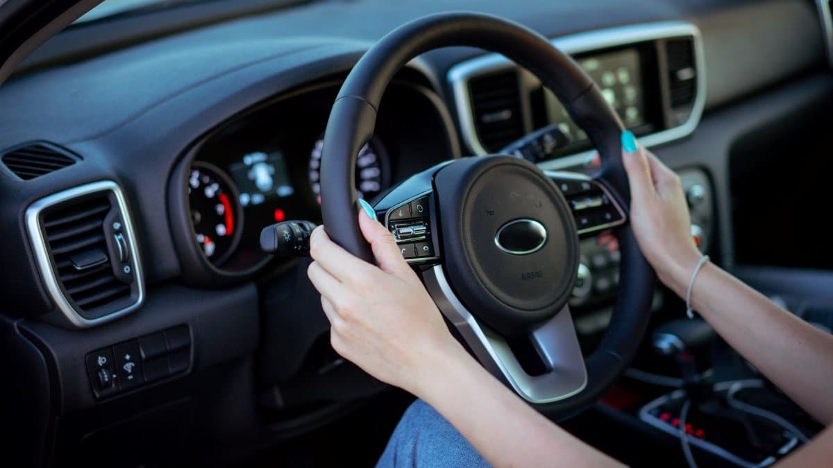 Close-up of a woman's hands on a steering wheel in a modern car interior.