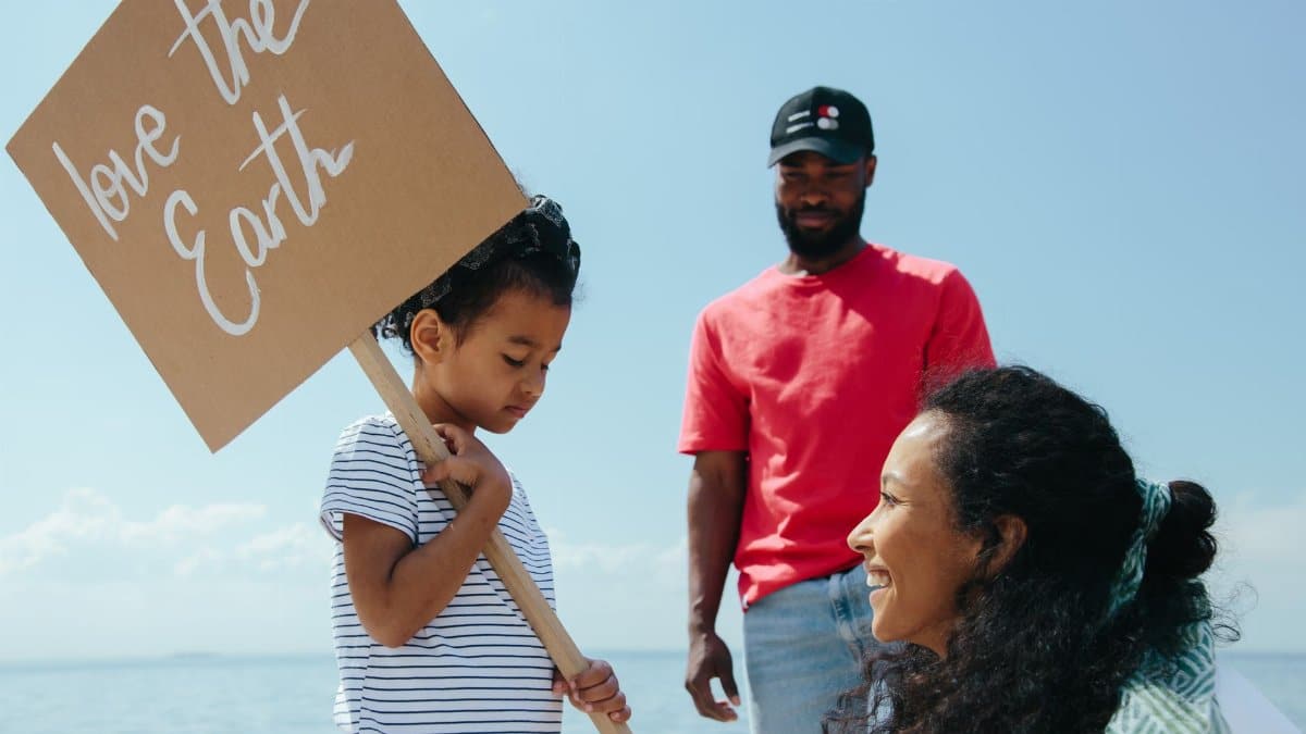 Family promoting love for Earth with a placard at a sunny beach.