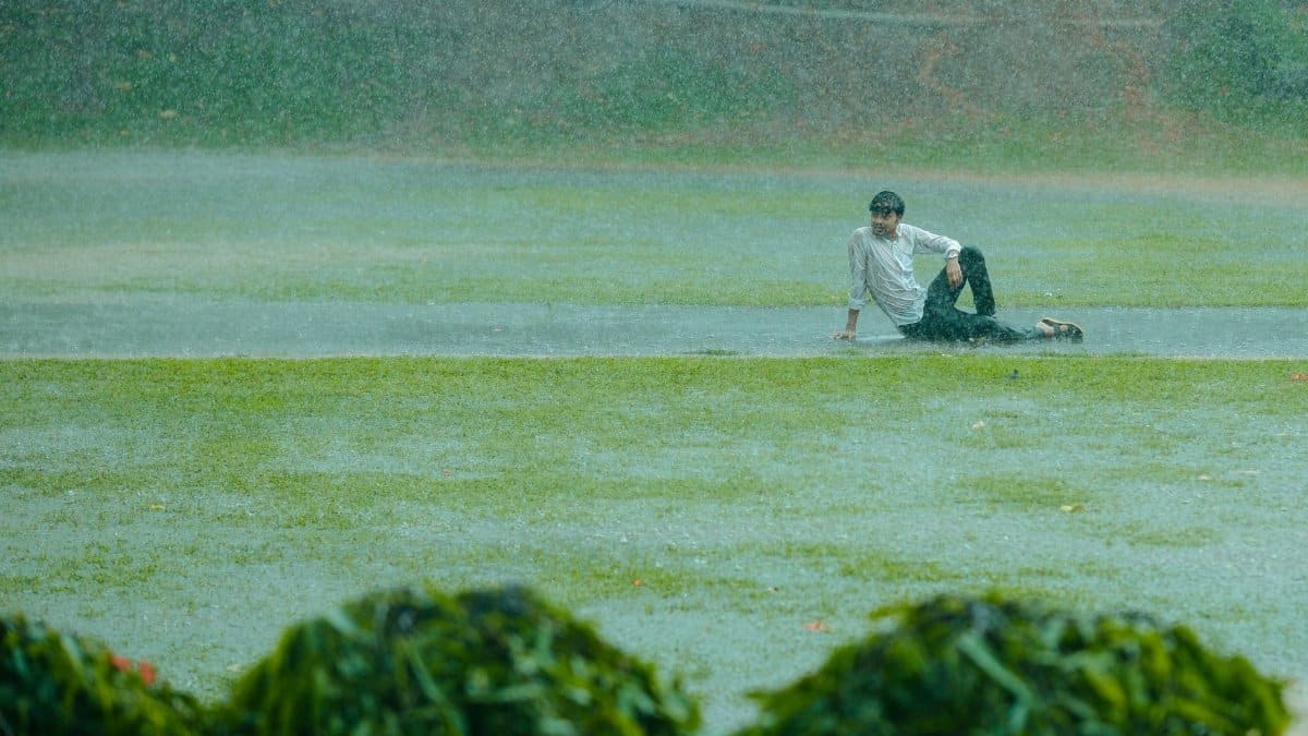 A man in casual attire enjoying playful moments in the rain