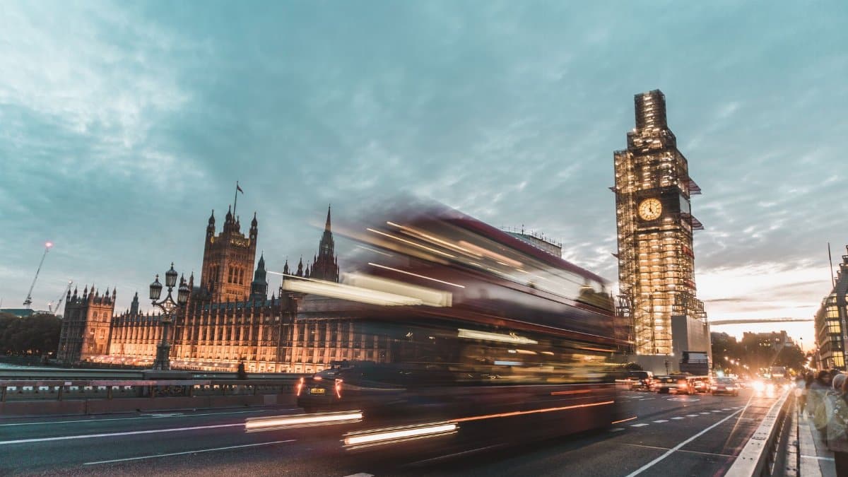 A long exposure shot of Big Ben and a double-decker bus in London during dusk.