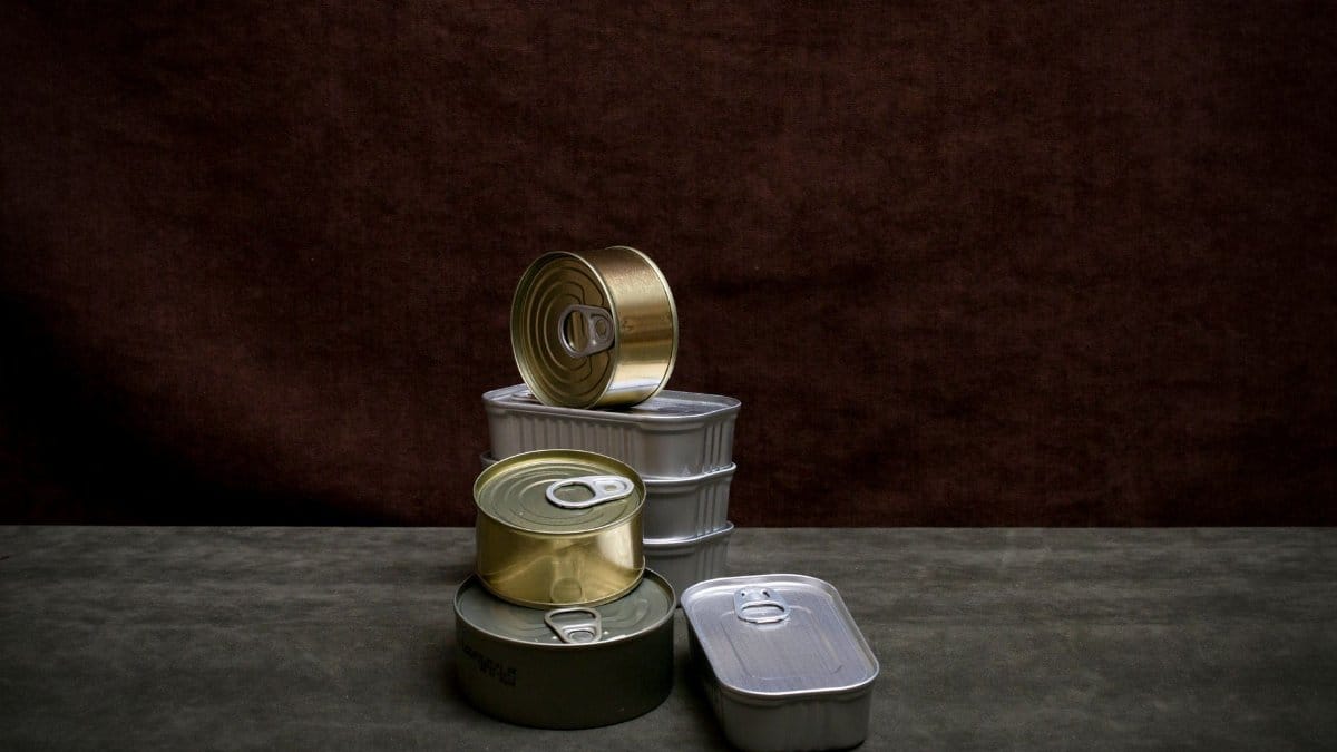A collection of various canned goods neatly arranged against a dark brown background.