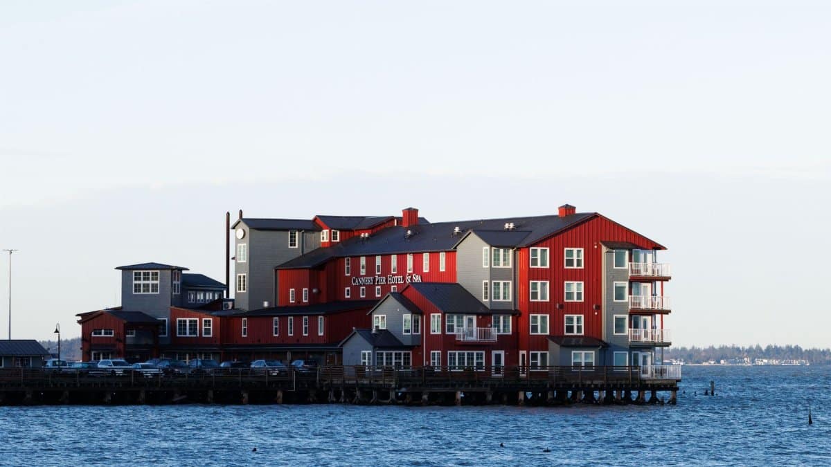 Red and grey waterfront hotel set against a serene ocean view during daylight.