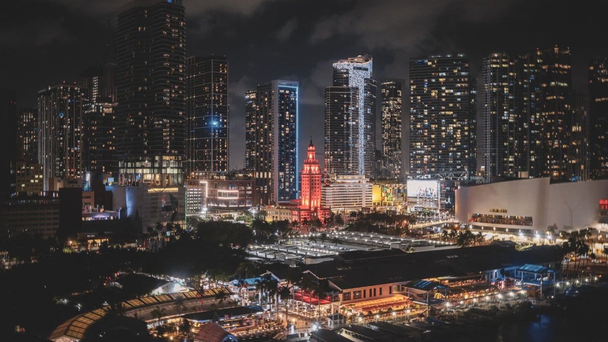 Vibrant Miami downtown skyline at night with illuminated skyscrapers and busy city vibes.