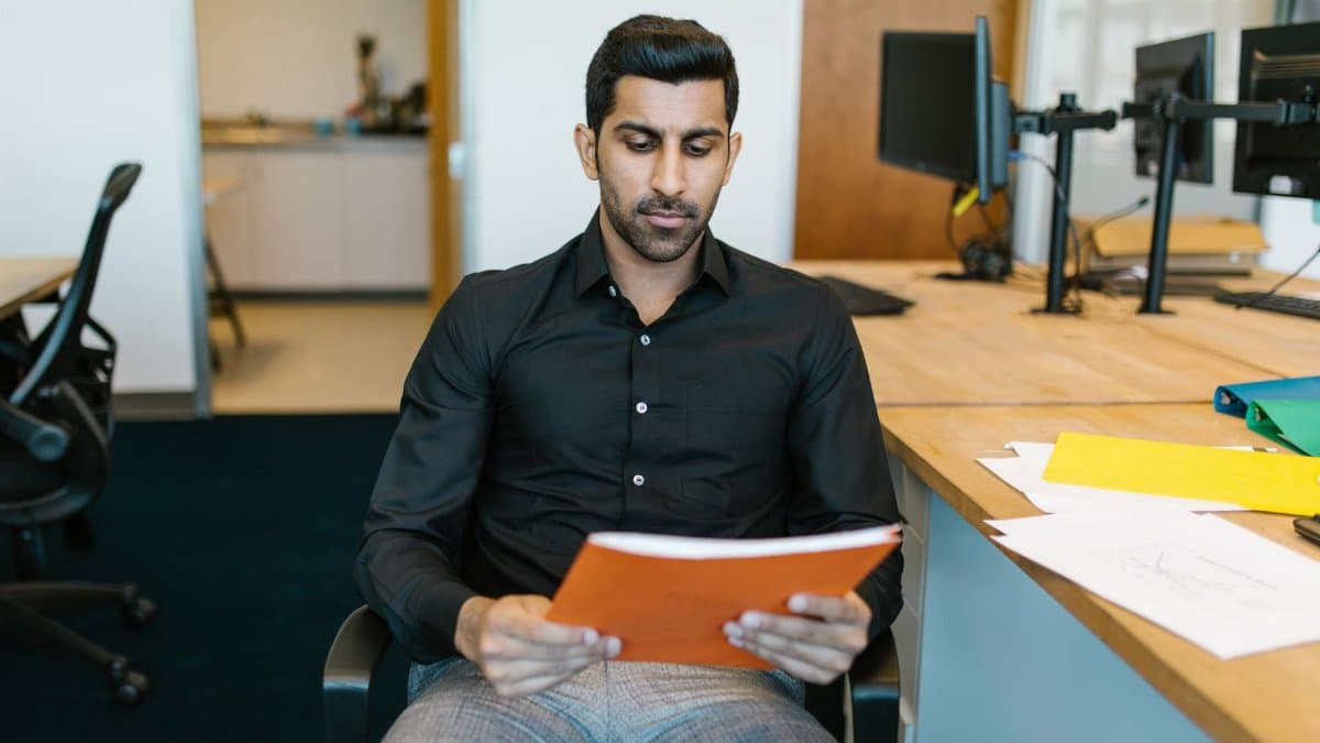 Serious businessman reviewing a document while sitting in a modern office.