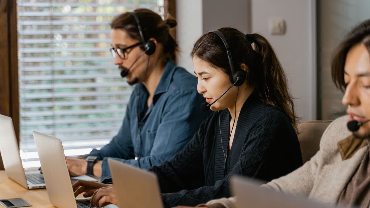 Team of professionals in a call center providing customer support using laptops and headsets.