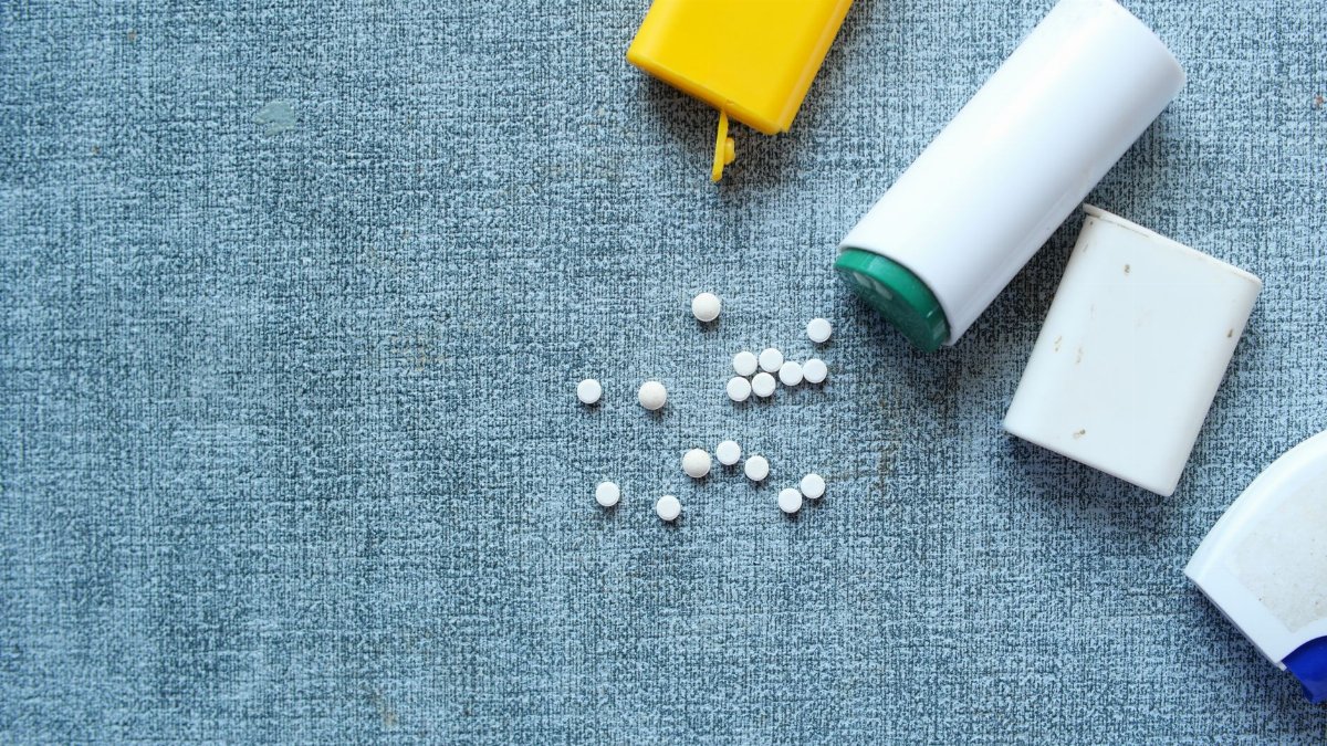 Top view of assorted pill containers and medication on a denim-like fabric surface.