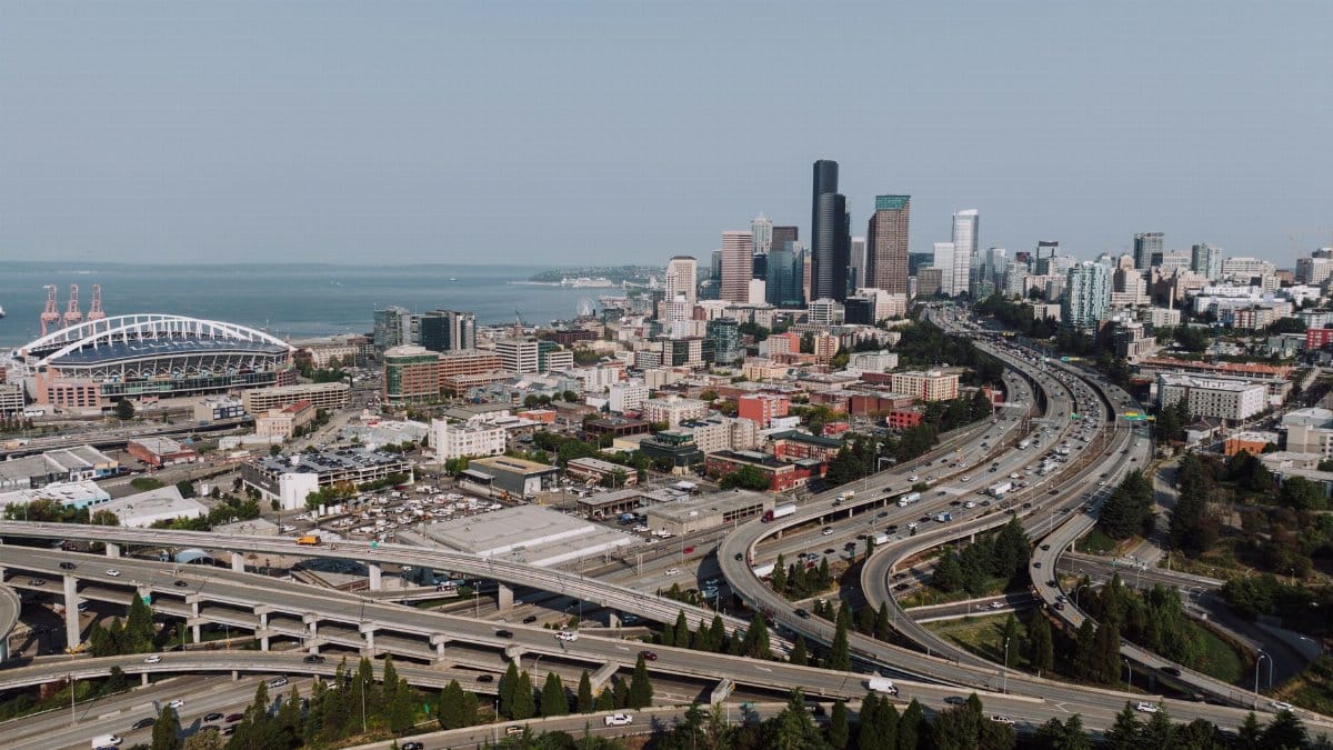 Aerial view of Seattle's downtown skyline with highways and waterfront on a clear day.