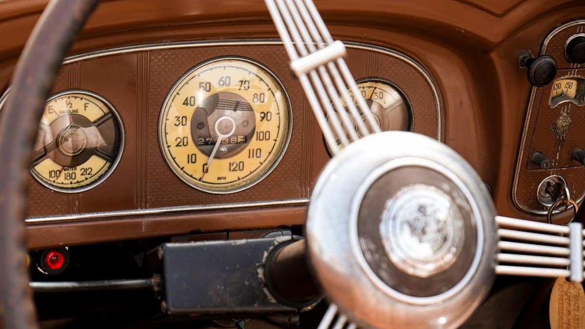 Close-up of a vintage car dashboard featuring classic analog gauges and steering wheel.