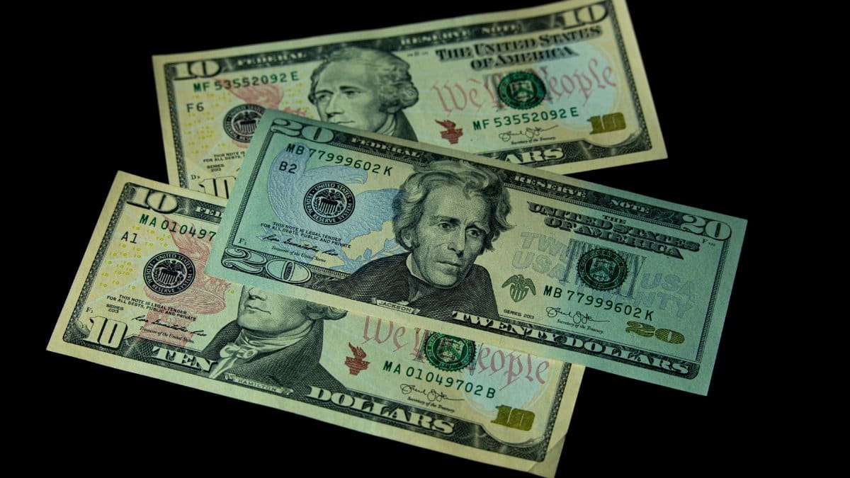 High angle view of US 10 and 20 dollar bills on a black background, emphasizing finance and currency themes.