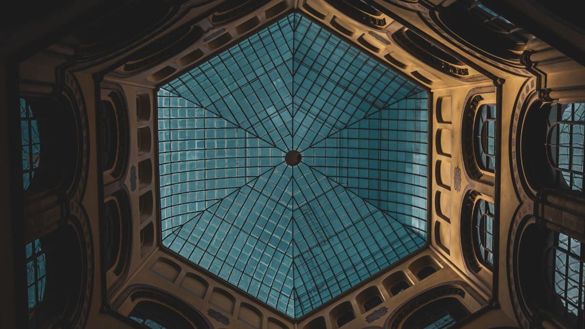 Dramatic view of a geometric glass ceiling in a historic building, showcasing intricate architectural details.