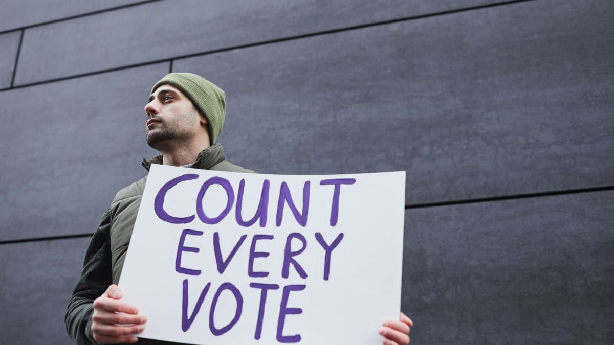 A man holding a 'Count Every Vote' placard, promoting democracy and voting rights.