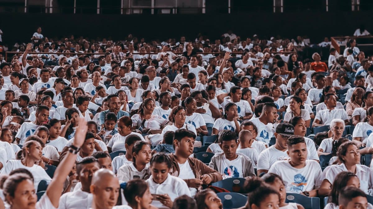 A diverse crowd in matching shirts at a stadium event indoors.