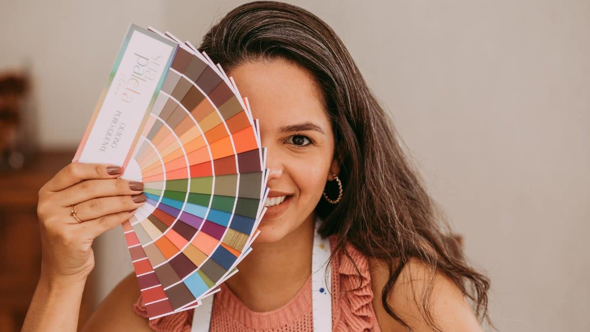 A smiling woman holds a color palette, perfect for creative and design themes.