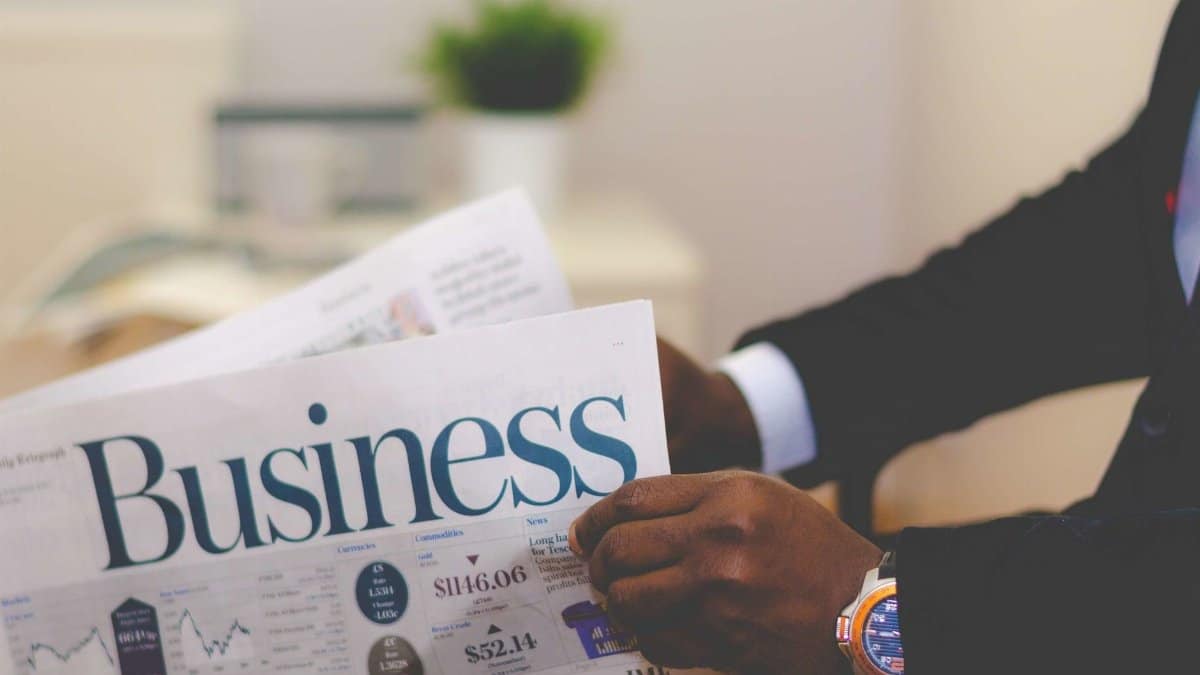 Close-up of a businessman reading a newspaper indoors, focusing on business headlines.