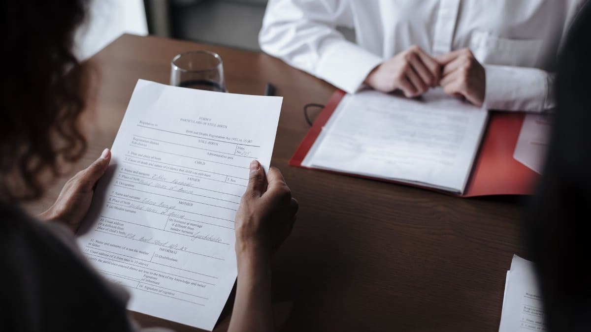 Two individuals discussing documents during a business meeting indoors.
