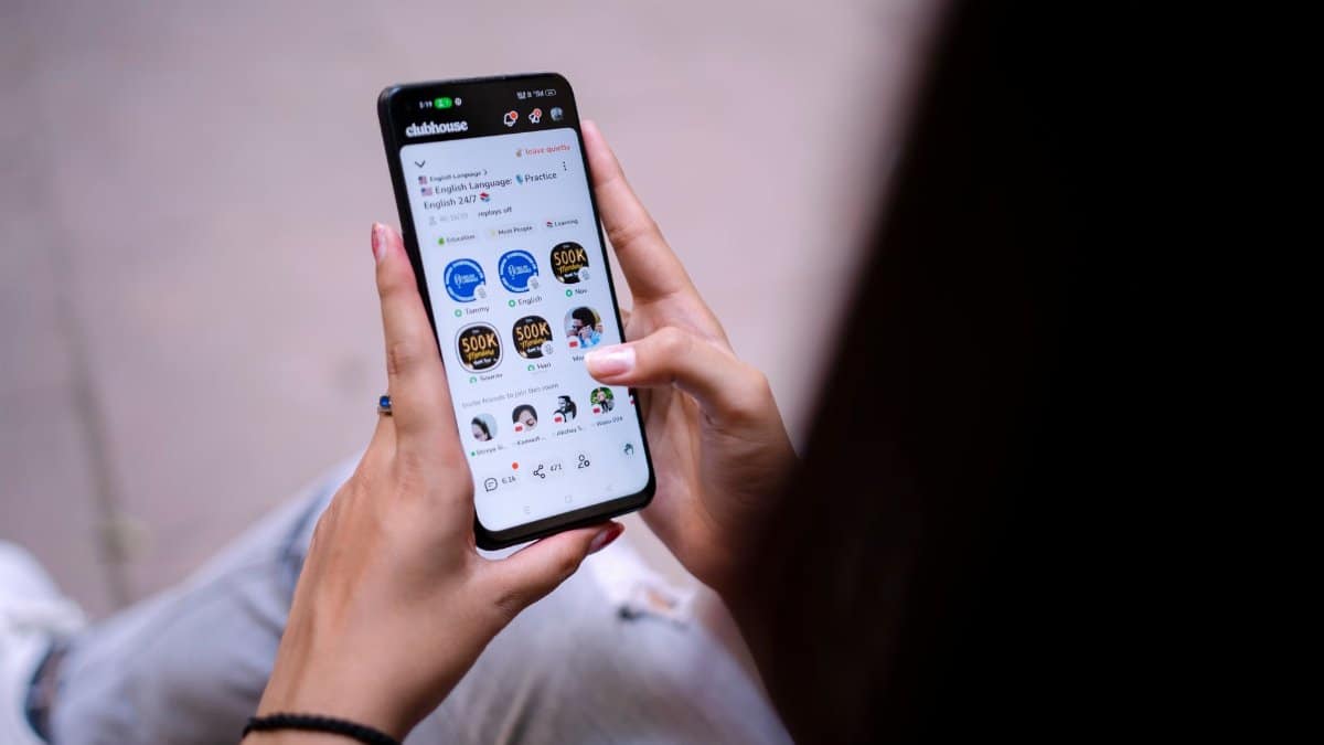 Close-up of a woman using a smartphone with social media app open. Hands holding device.