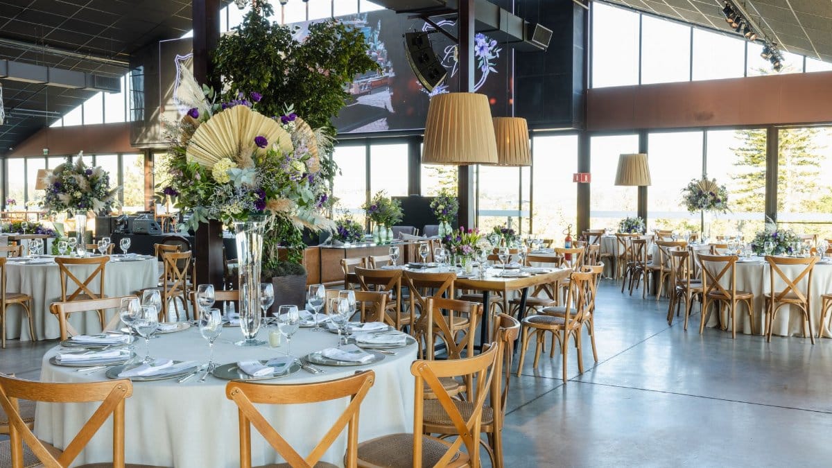 A beautifully decorated wedding reception hall with floral arrangements, elegant lighting, and arranged tables.