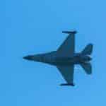 An F-16 fighter jet captured mid-flight against a clear blue sky, showcasing military aviation prowess.