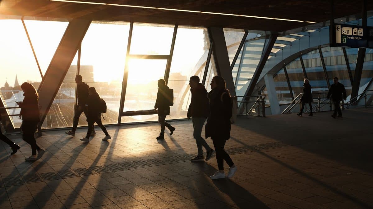 Commuters silhouetted against sunrise light in a modern train station, capturing the essence of daily routine.