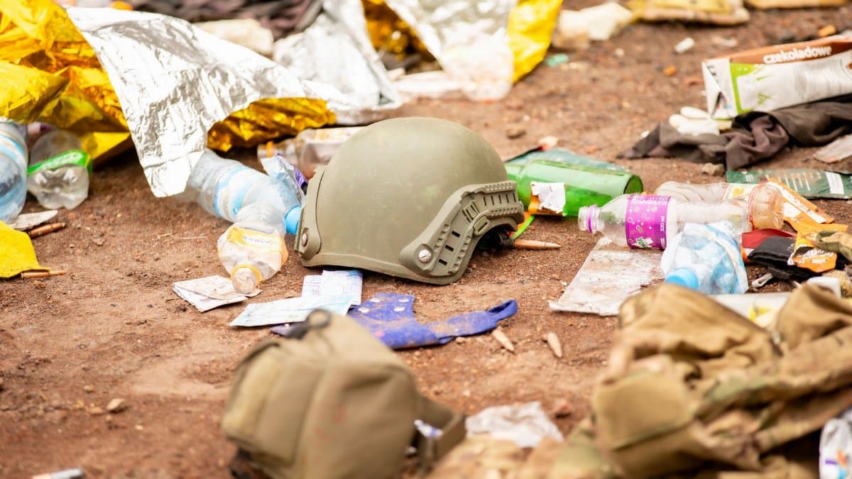 Abandoned military helmet surrounded by litter and debris, depicting a chaotic scene.