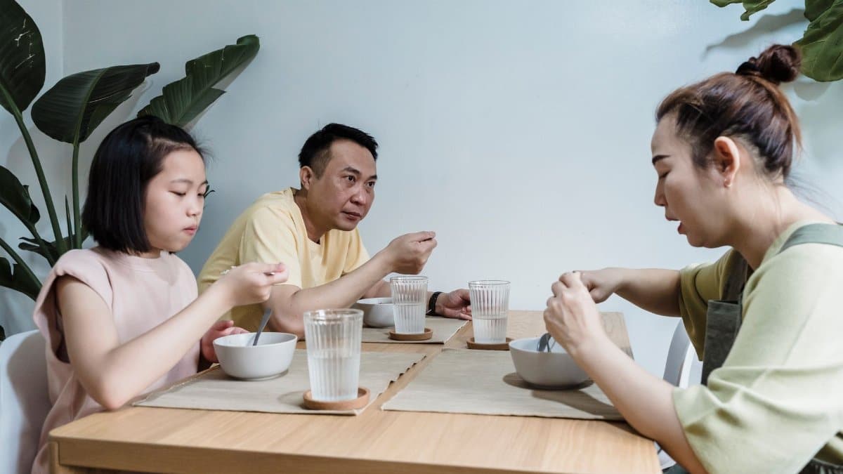 Asian family seated at dining table enjoying breakfast together indoors.