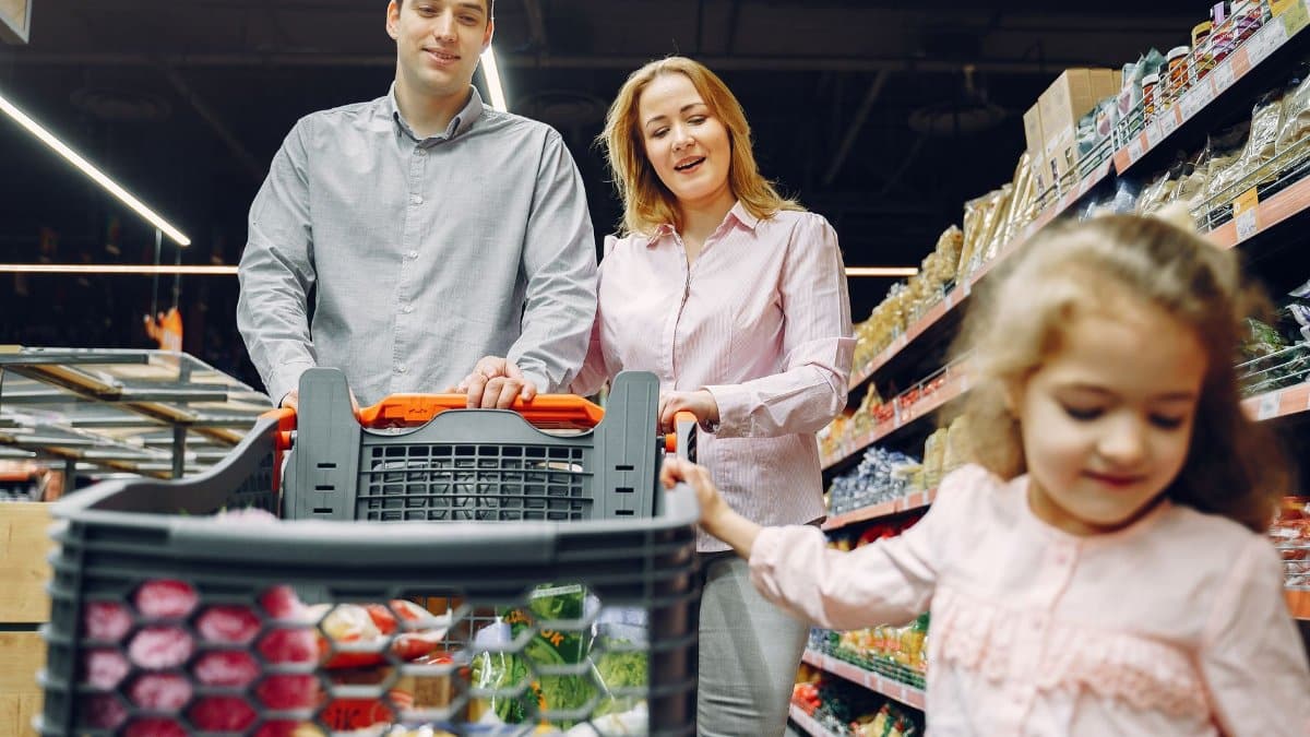 Happy family enjoying a fun shopping trip together in a supermarket aisle.