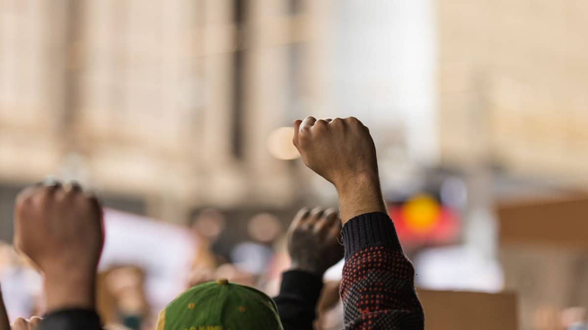 A powerful image of raised fists symbolizing unity during a protest in Melbourne's streets.