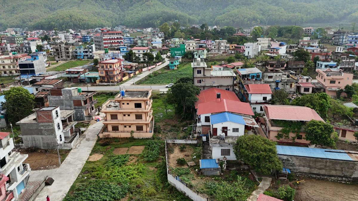 An aerial view of vibrant residential buildings nestled in a lush Nepalese landscape.