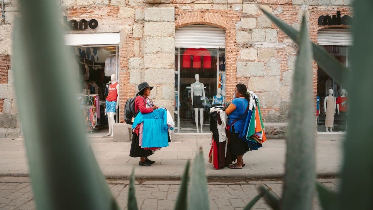 Colorful street scene in Oaxaca featuring local vendors selling clothing near a boutique.