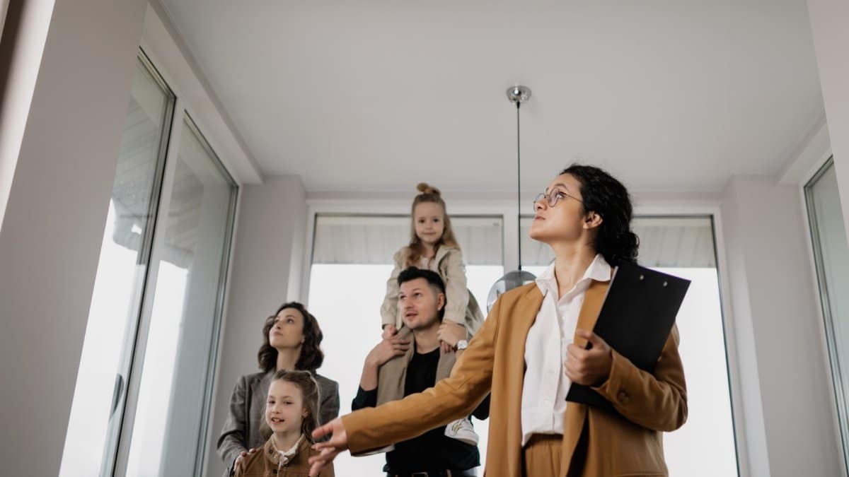 A family with children tours a modern home guided by a real estate agent.