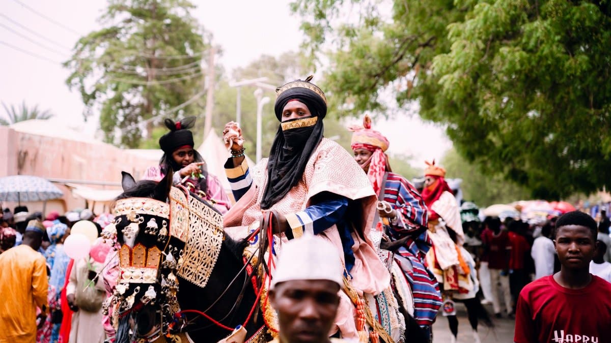 Vibrant scene from a Durbar Festival parade featuring culturally dressed riders and decorated horses.