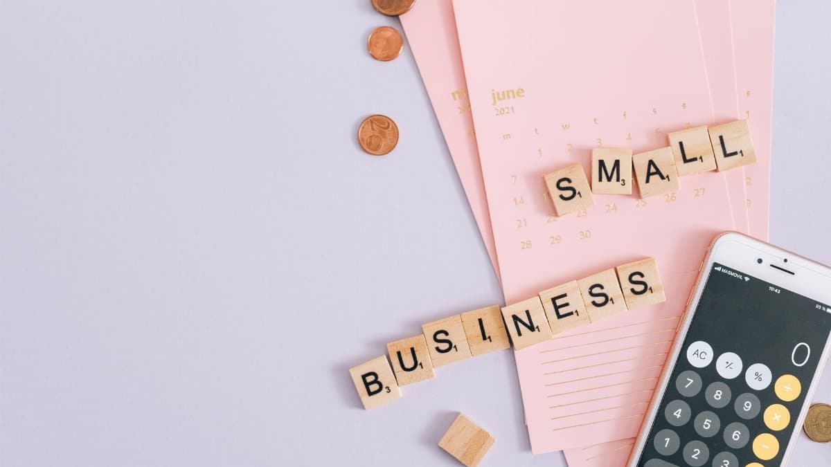 A top view image of small business tools including a calendar, coins, and a smartphone calculator.