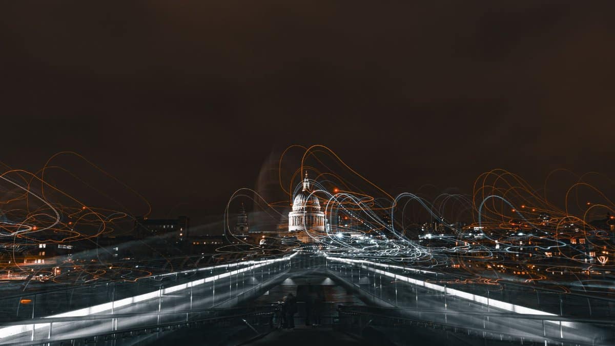Dynamic night shot of Millennium Bridge with light trails leading to St Paul's Cathedral in London.