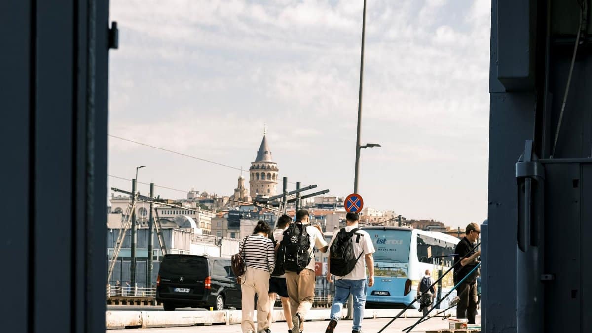Tourists walking near the iconic Galata Tower in Istanbul under a vibrant sky, showcasing the city's cultural essence.