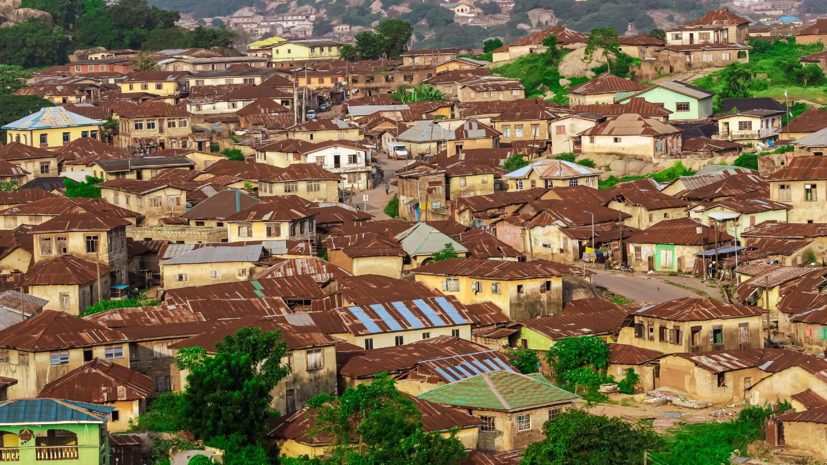 Aerial view of a rustic townscape with brown-roofed houses and lush trees.