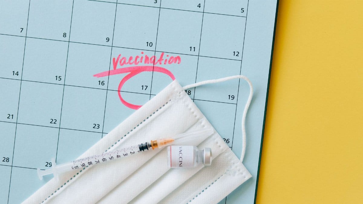 Close-up of a calendar marked for vaccination, with a syringe and face mask highlighting healthcare theme.