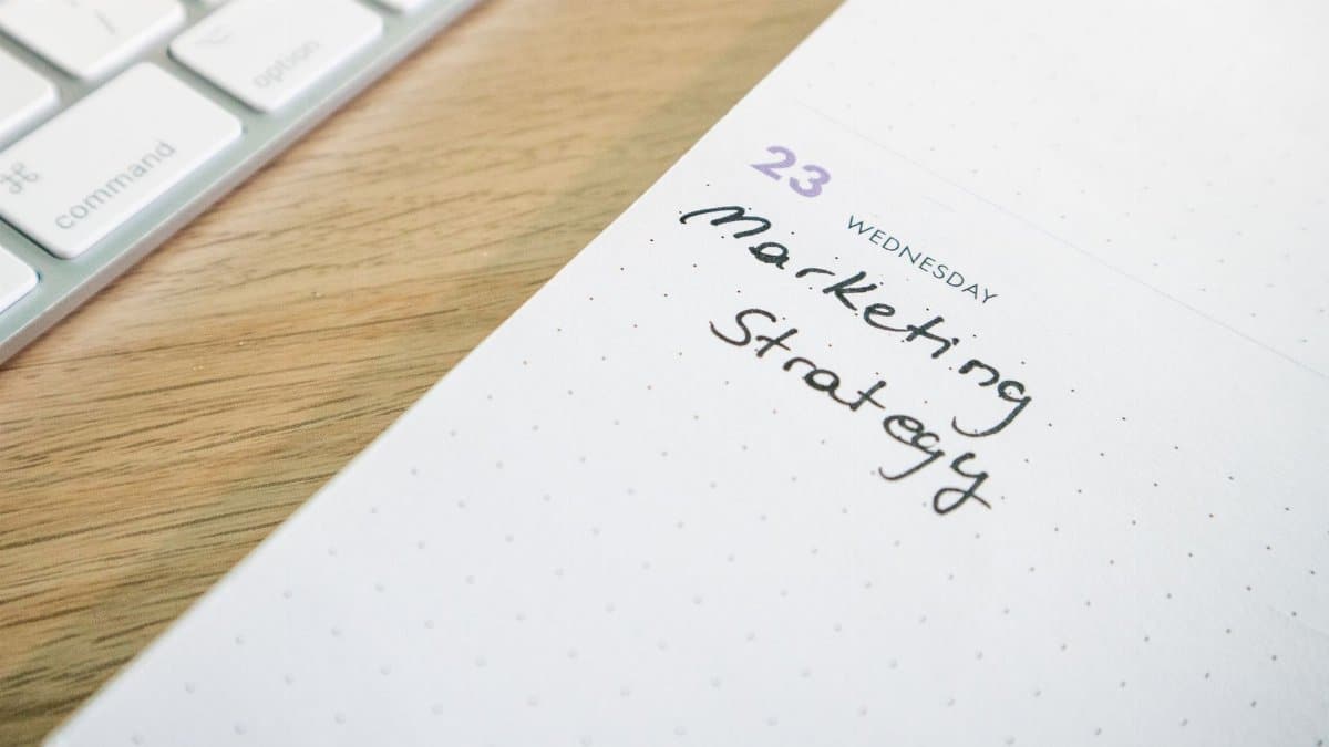 Close-up of a planner with 'Marketing Strategy' handwritten alongside keyboard.