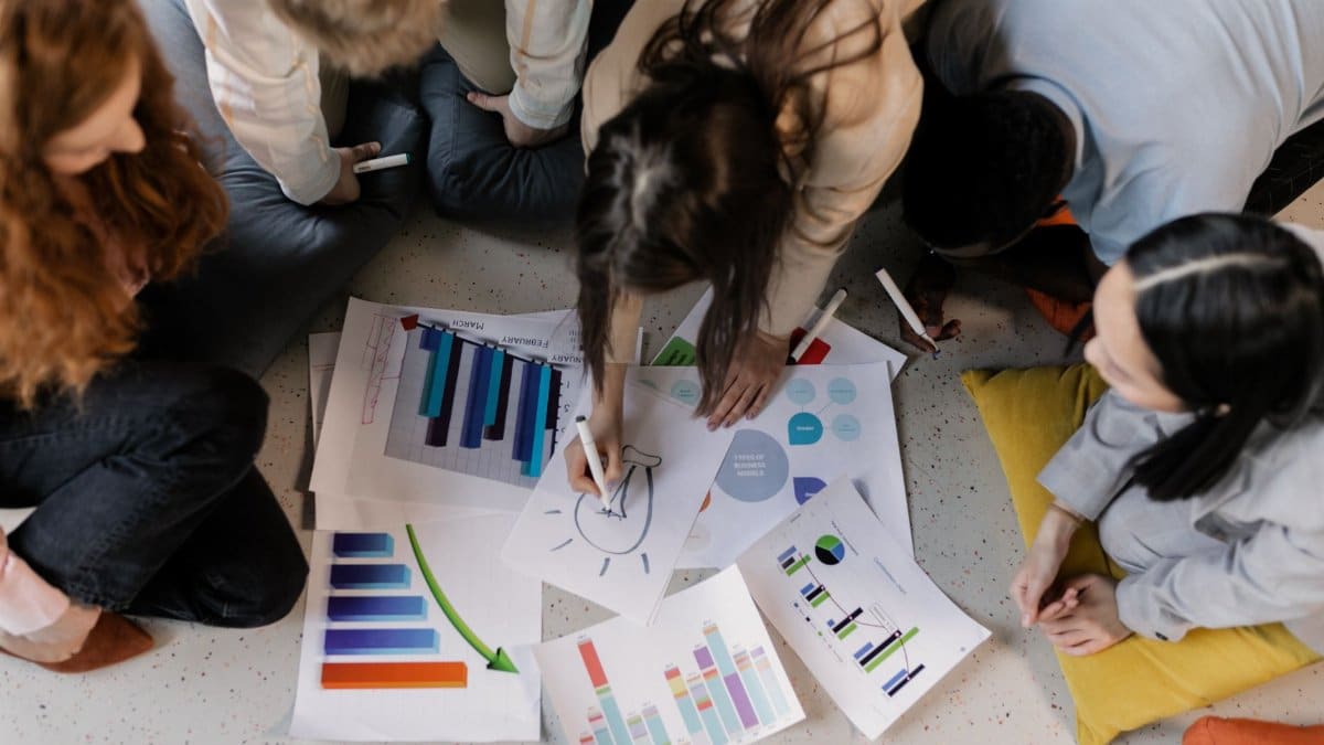 Overhead view of diverse team brainstorming on business strategy using charts and graphs.