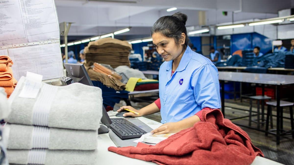 Female factory worker inspecting textiles for quality control in a busy production facility.
