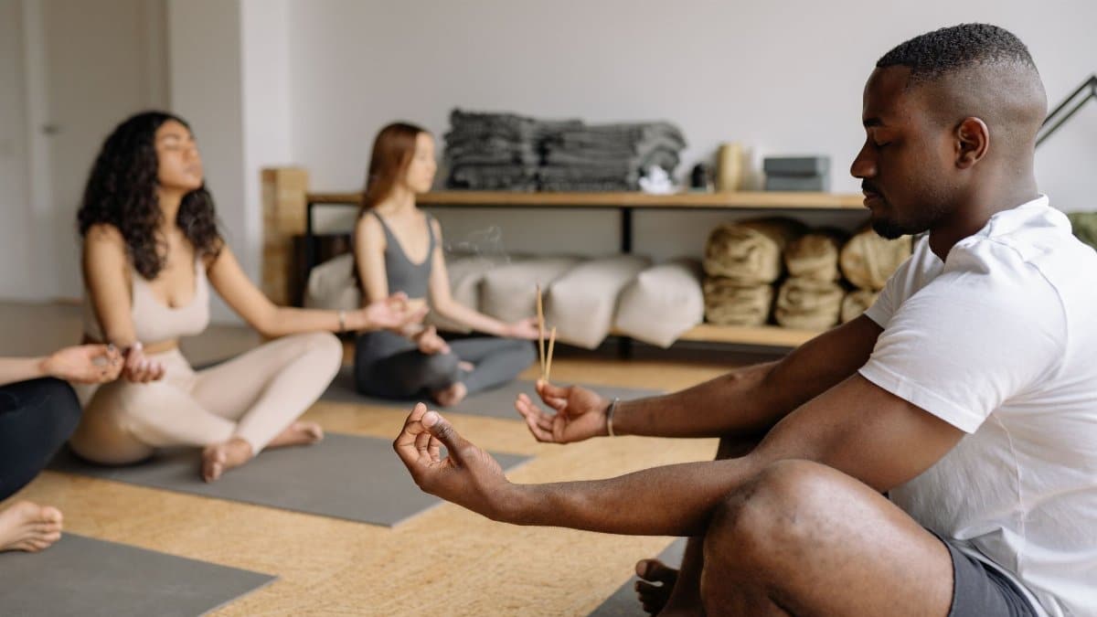 A diverse group practicing mindfulness meditation with incense in a serene indoor setting.