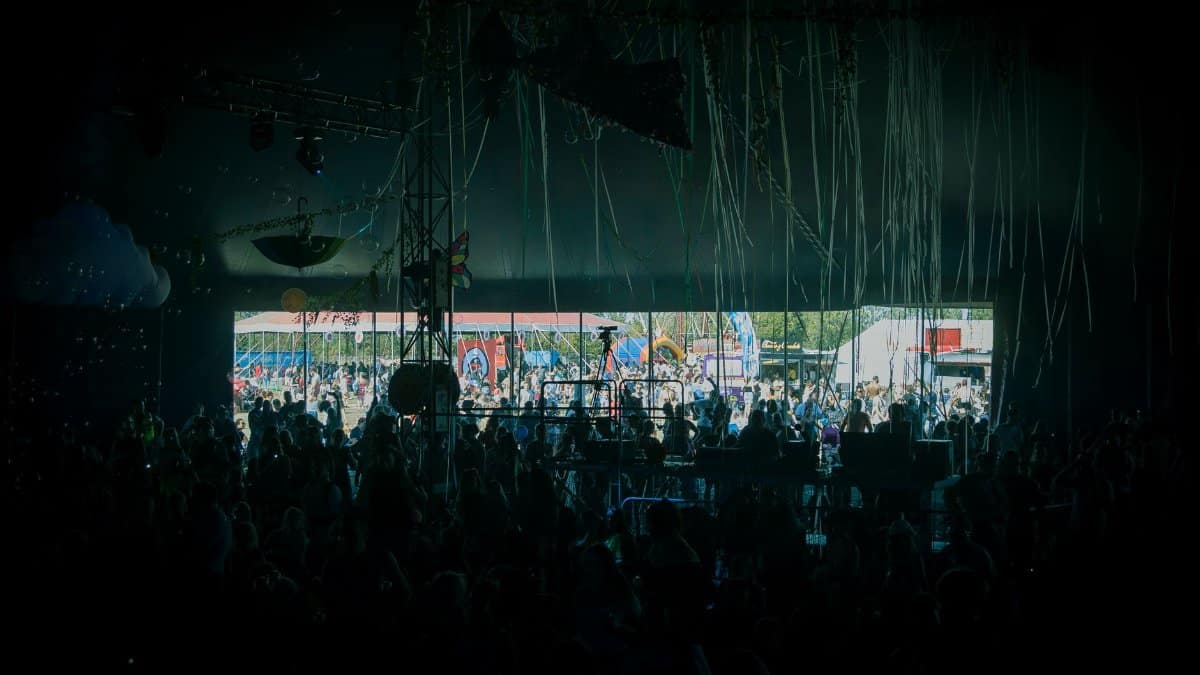 A crowd enjoying live music at a colorful outdoor festival stage.