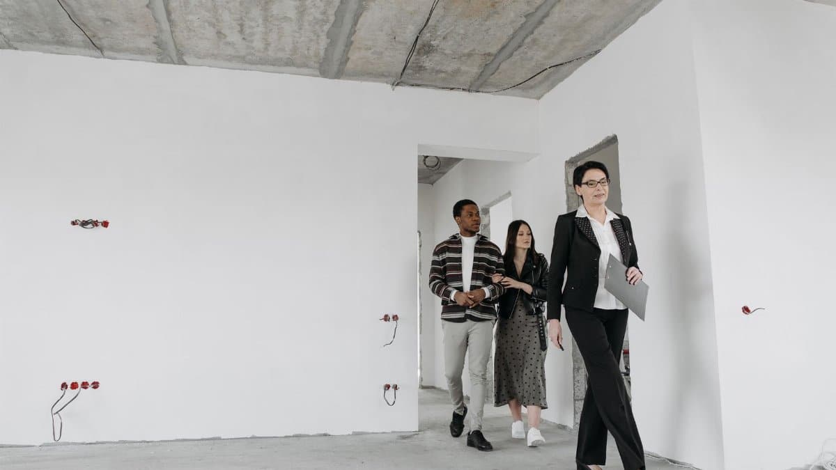 Real estate agent showing an unfinished house to potential buyers during a viewing session.