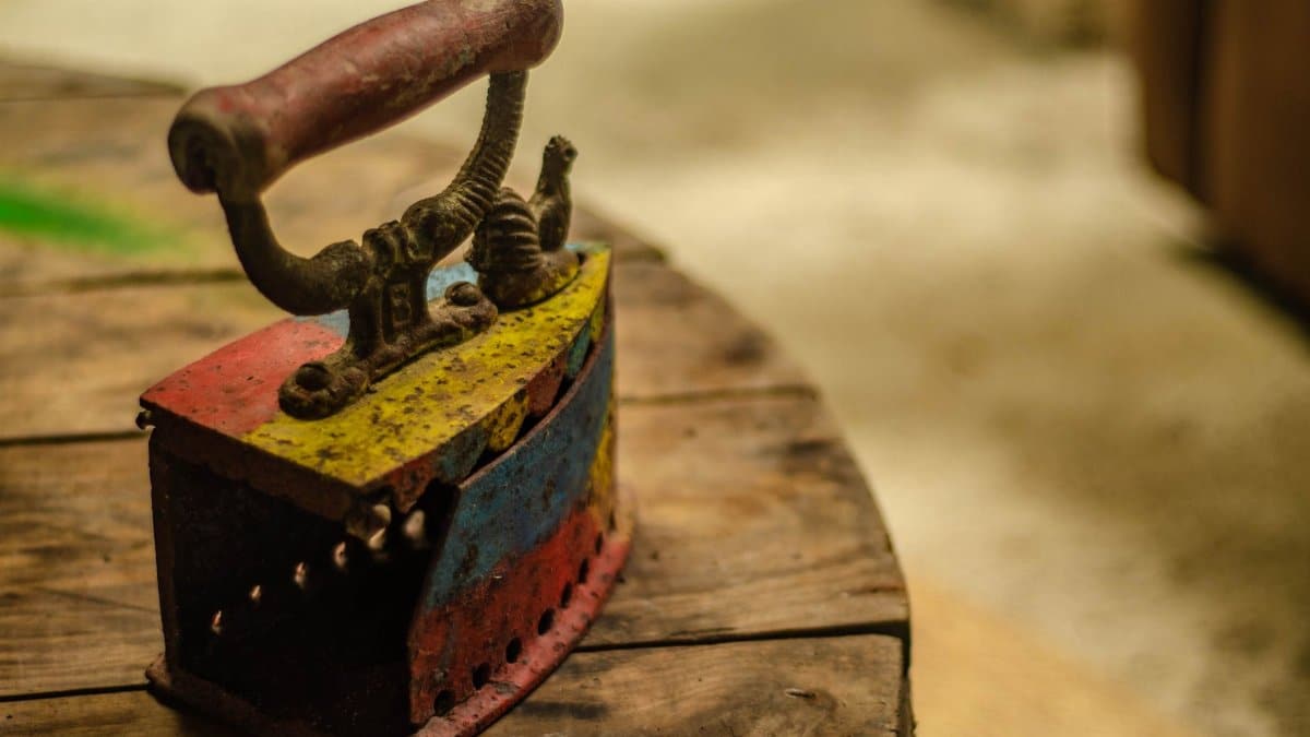 A close-up of a colorful vintage iron placed on a rustic wooden table, highlighting its antique charm.