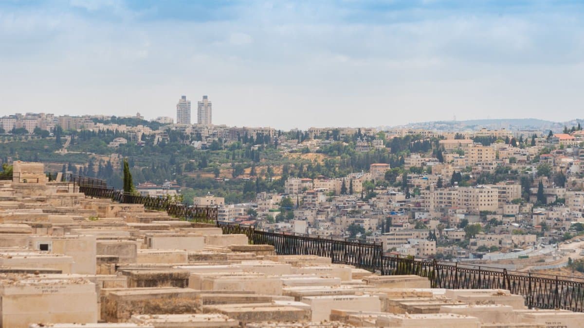 Scenic view of Jerusalem, Israel, featuring a historic cemetery and urban landscape under a blue sky.