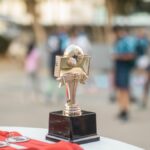 Close-up of a polished soccer trophy with medals at an outdoor sports award ceremony.